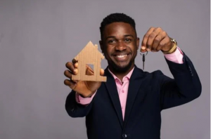 estate agent holding a model of a house and keys